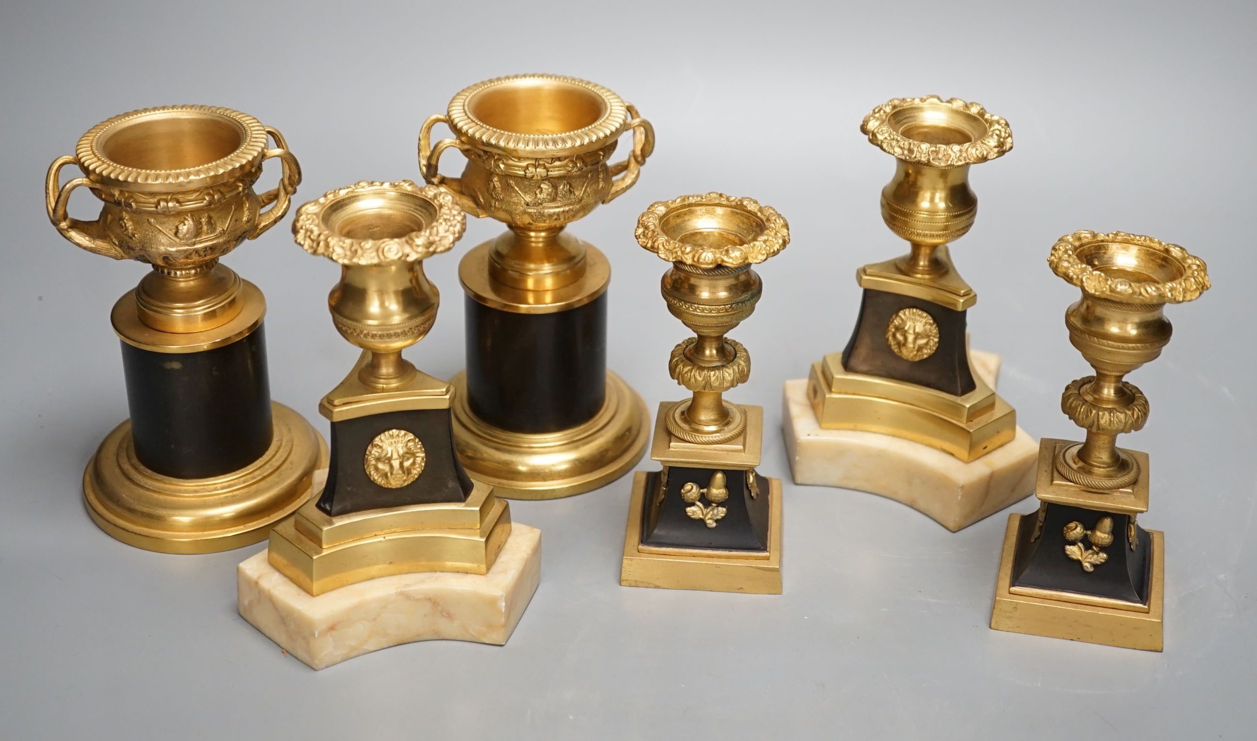 A pair of Louis XVI style ormolu and bronze models of campana urns and two similar pairs of Empire style candlesticks